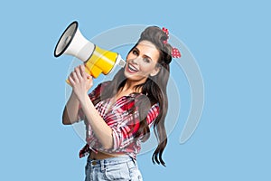 Beautiful pin up woman shouting into megaphone, advertising your product on blue studio background