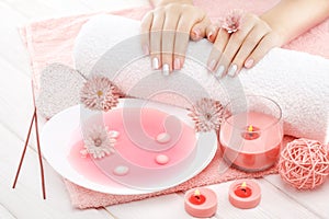 Beautiful pinc manicure with chrysanthemum flower and towel on the white wooden table. spa photo