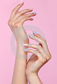 Beautiful pink and blue manicure with crystals on female hand. Close-up.