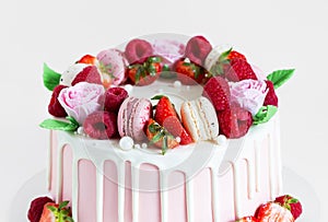 Beautiful pink cake decorated with macarons, raspberries, strawberries and sugar rose flowers
