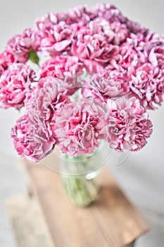 Beautiful pink carnation flowers in a vase on a table . Bouquet of light pink flower. Decoration of home. Wallpaper and