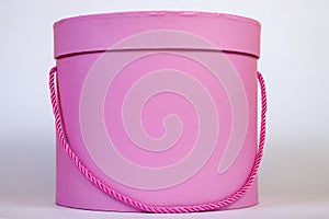 A beautiful pink circular gift box for packing a surprise inside with a closed lid and a cord instead of a ribbon close-up on a