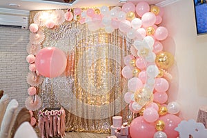 Beautiful pink decorations, wrapped present boxes with ribbons and bow, flowers and balloons on golden shiny background.