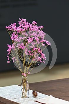 Beautiful pink flower in vases glass on the wooden table with black wall interior for office building or home and living