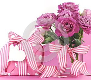 Beautiful pink gift and roses on pink and white background with copy space