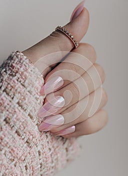 Beautiful pink nail manicure. Stylish pastel pink manicure. Nail polish. Female hands manicure close up view on pink knitted blzer