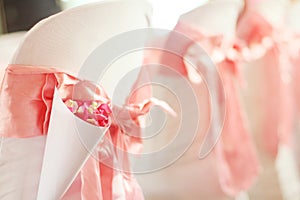 Beautiful Pink Rose petals Flowers with pink ribbon decoration on chairs in wedding event hall
