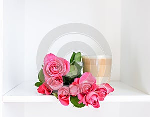 Beautiful pink roses bouquet and the transparent glass cup of hot latte on soft background