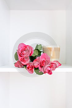 Beautiful pink roses bouquet and the transparent glass cup of hot latte on white background