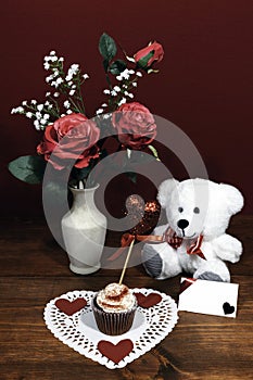 Beautiful pink roses in a vase accented with Baby`s Breath flowers, heart shaped white dollie with a decorated cup cake with a he