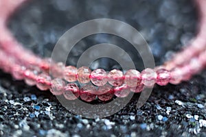 Beautiful pink strawberry quartz beads on a black glitter background close-up macro photo