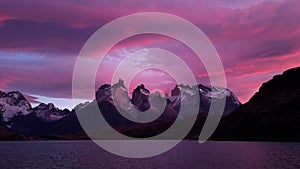 Beautiful pink sunset with view on mountain lake with scenic rocks on first plan in Torres del Paine Park in Patagonia.