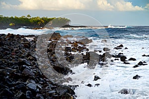 Beautiful pink tinted waves breaking on a rocky beach at sunrise on east coast of Big Island of Hawaii