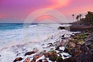 Beautiful pink tinted waves breaking on a rocky beach at sunrise on east coast of Big Island of Hawaii