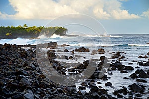 Beautiful pink tinted waves breaking on a rocky beach at sunrise on east coast of Big Island of Hawaii