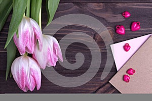 Beautiful pink tulips with on wooden background with envelopes and purple heart. Copy space. Valentines Day.Wedding