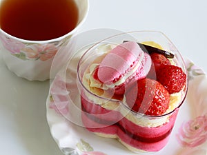 Beautiful pink yogurt cake decorate with macaron and strawberry and cup of tea