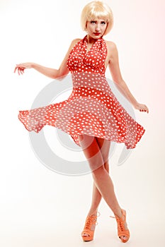 Beautiful pinup girl in blond wig and retro red dress dancing. Party.