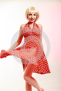 Beautiful pinup girl in blond wig and retro red dress dancing. Party.