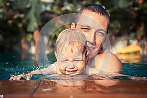 Beautiful playful child baby kid smiling parent father together fun swimming pool splashes