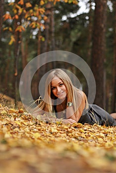 Beautiful playful girl relaxing on yellow leaves