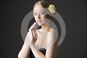 Plus size blonde with a yellow rose in her hair posing on a gray seamless background