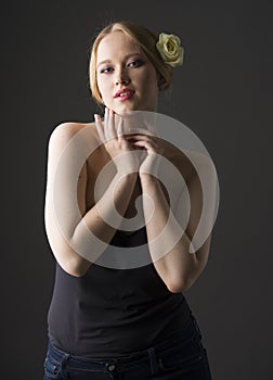 Plus size blonde with a yellow rose in her hair posing on a gray seamless background