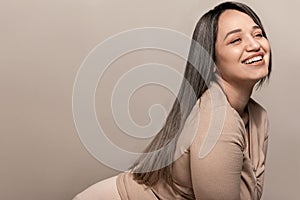 Beautiful plus size model with long colored glossy hair posing on beige studio background