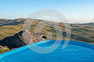 Beautiful pool with mountain landscape view with wind turbine eolic renewable energy in Boulder Penedo house in Fafe, Portugal