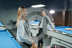 beautiful pool player smiling while standing leaning on the billiard table
