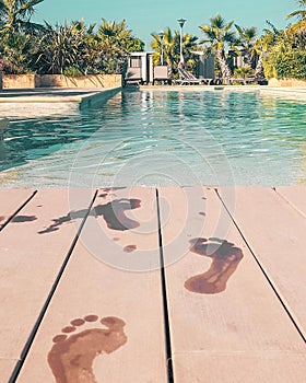 Beautiful pool surrounded by palm trees and the footprints on the poolside