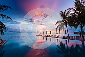 Beautiful poolside and sunset sky. Luxurious tropical beach landscape, deck chairs and loungers and water reflection