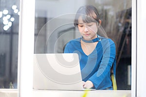 Beautiful portrait asia young woman working online on laptop sitting at cafe shop, professional female freelance using notebook