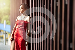 Beautiful portrait asian woman dress in red fashion evening dress act like model and lean on wooden wall