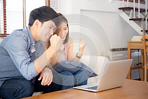 Beautiful portrait asian young couple working laptop with smile and happy sitting on couch at living room
