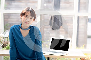 Beautiful of portrait asian young woman sitting looking camera and laptop on table at coffee shop