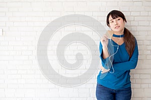 Beautiful portrait asian young woman standing happy enjoy and fun listen music with headphone on cement concrete background