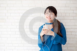 Beautiful portrait asian young woman standing happy enjoy and fun listen music with headphone on cement concrete background.