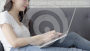 Beautiful portrait asian young woman working laptop with smile sitting on couch at living room