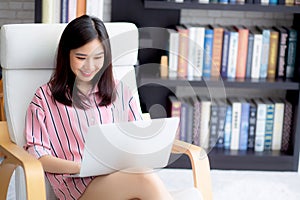 Beautiful of portrait asian young woman working online laptop sitting on chair at living room