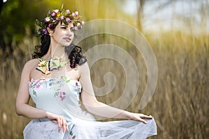 Beautiful Portrait of Caucasian Brunette Lady with Unique Flowery Chaplet and Butterflies. Posing Against Nature Background