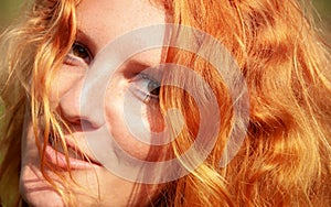 Beautiful portrait in closeup of a smiling young red-haired curly woman