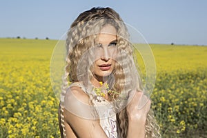 Beautiful portrait of a countryside girl posing over yellow field background.