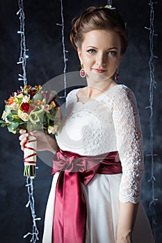 Beautiful portrait of a gentle cute happy bride in a white dress with a bright little colored bouquet