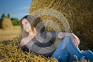 Beautiful portrait of a girl against a background of straw with natural light.