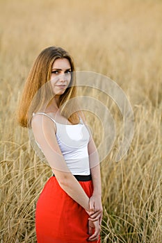 A beautiful portrait of a girl in a red skirt. Wheat field by a pretty girl.