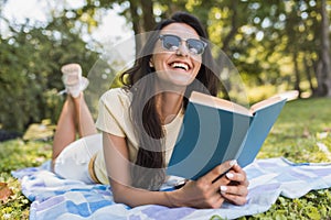 Beautiful portrait of a gorgeous young brunette woman reading a book in the park. Happy female student reading and learning a