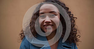 Beautiful portrait of happy calm mixed race 20-25 woman with curly hair looking right, posing at camera slow motion.