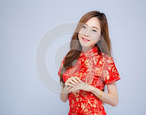 Beautiful portrait happy Chinese New Year young asian woman wear cheongsam fashion smile with gesture congratulation
