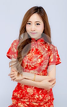 Beautiful portrait happy Chinese New Year young asian woman wear cheongsam smile with gesture congratulation and greeting